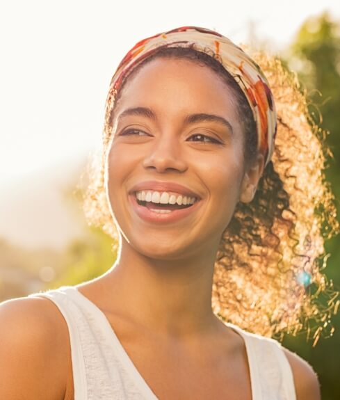 Woman with ponytail smiling outdoors after cosmetic dentistry in Worcester