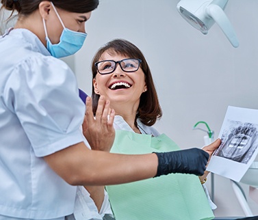 Woman smiling at dentist holding X-ray