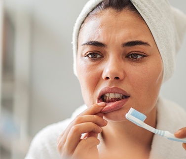 A woman looking at her gums in the mirror