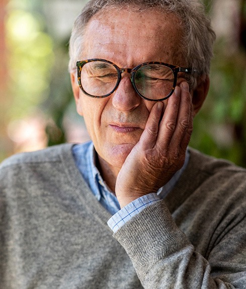 Man with glasses experiencing toothache