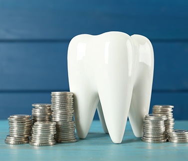 A large ceramic model of a tooth surrounded by stacks of coins